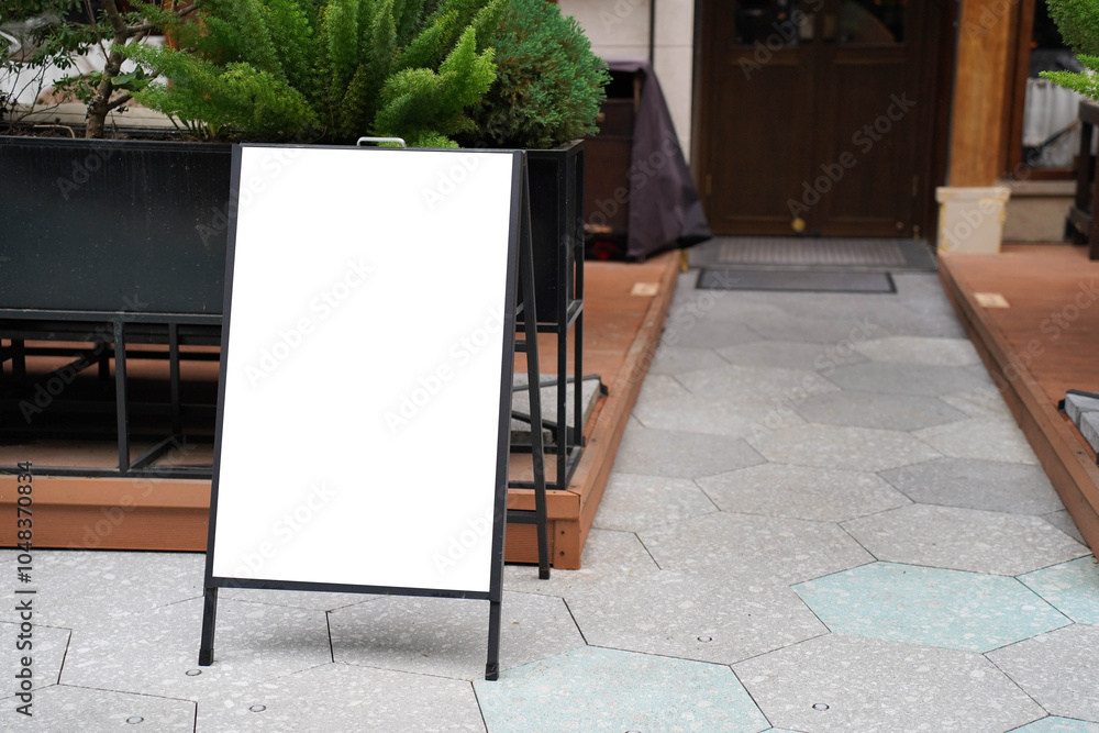 Blank white outdoor advertising stand sandwich board mock up template. Clear street signage board placed by an outdoor dinning area of a restaurant.