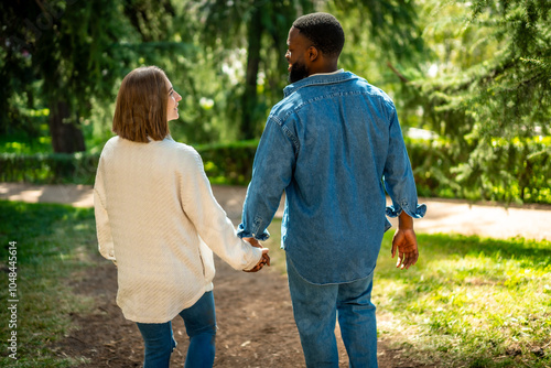 Rear view of a multi-ethnic couple walking along a park