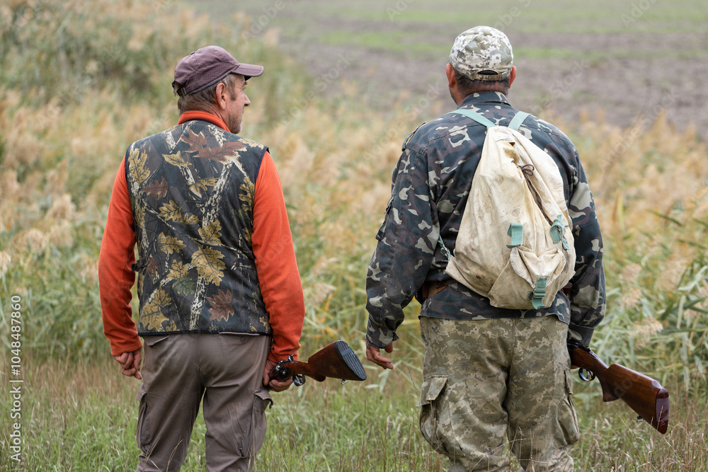 Mature hunter man holding a shotgun and walking through a field Mature hunter man holding a shotgun and walking through a field