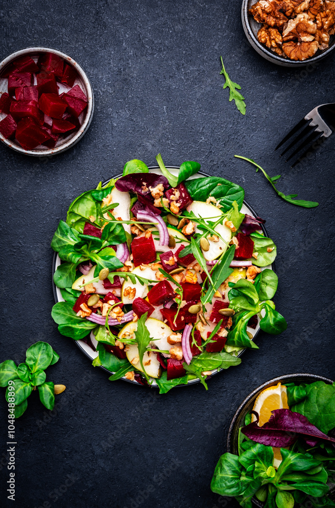 Φωτογραφία Yummy vegan salad with beet, pear, nuts, pumpkin seeds and lettuce, black backgr