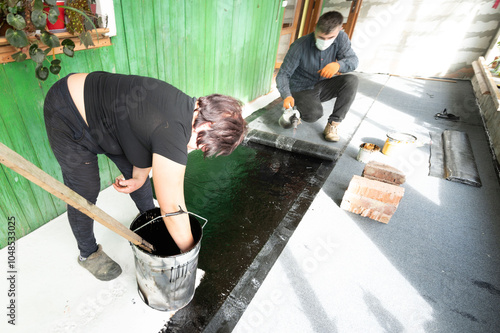 A man and a woman are engaged in waterproofing the floor in the house.