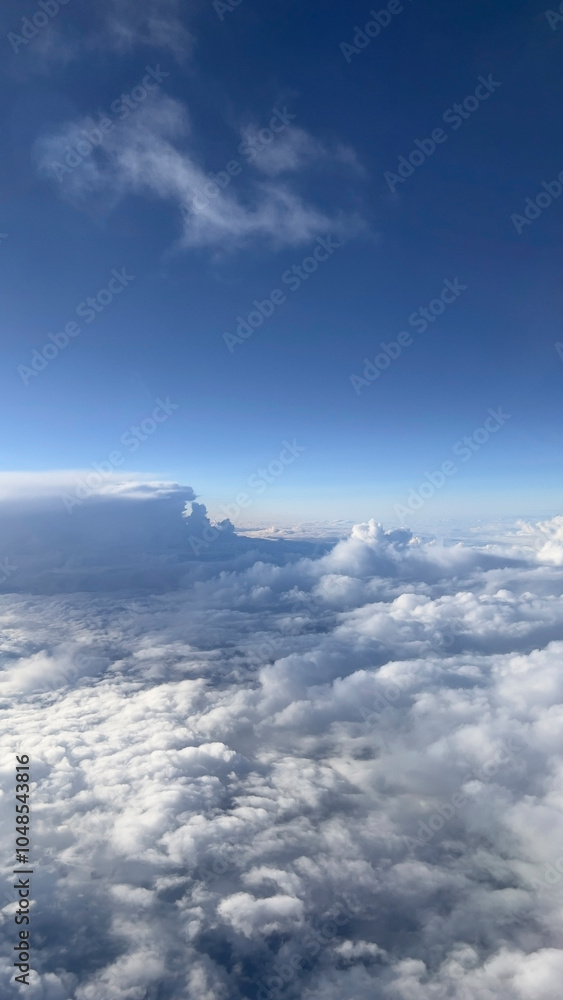 View above clouds on blue sky background. View from airplane window. View above clouds on blue sky background. View from airplane window.