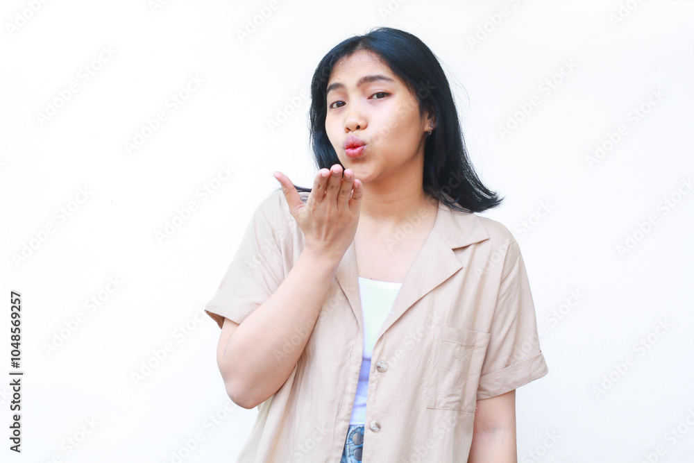 happy asian woman blowing kiss with raising palm wearing brown casual clothes isolated on white background happy asian woman blowing kiss with raising palm wearing brown casual clothes isolated on white background