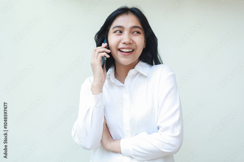 portrait of carefree asian young woman executive speaking on smartphone with excitement face expression arms folded looking away wearing white formal suit shirt, standing isolated portrait of carefree asian young woman executive speaking on smartphone with excitement face expression arms folded looking away wearing white formal suit shirt, standing isolated