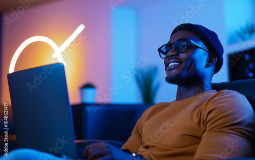 A man laughs and watches a video channel on the Internet from his living room, sitting on a sofa, the concept of developing video blogging and popularizing video content photo