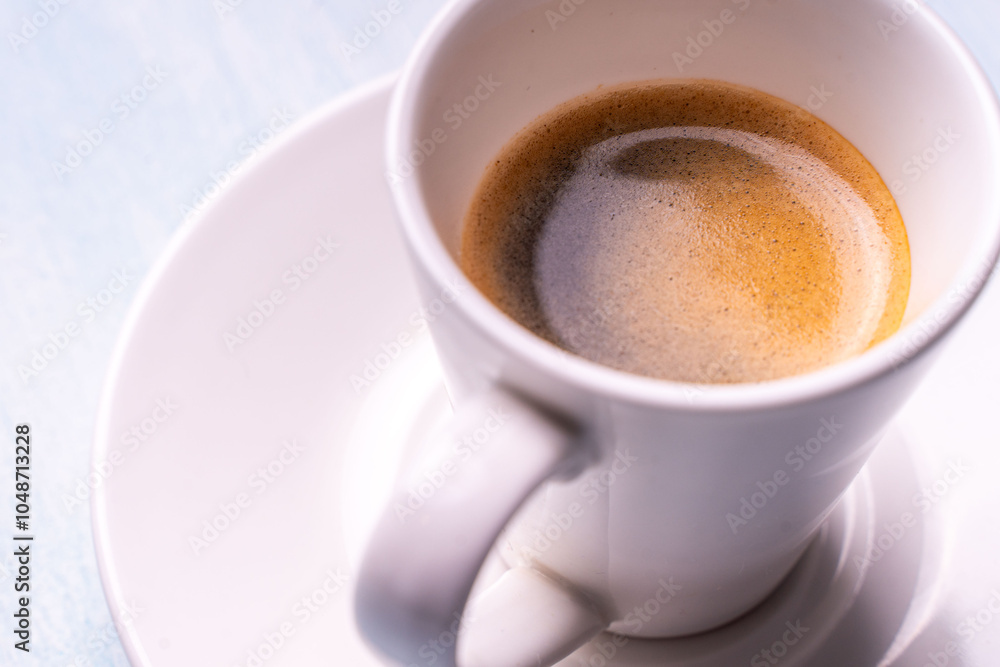 Black espresso coffee in a white cup and saucer on a light background. Black espresso coffee in a white cup and saucer on a light background.