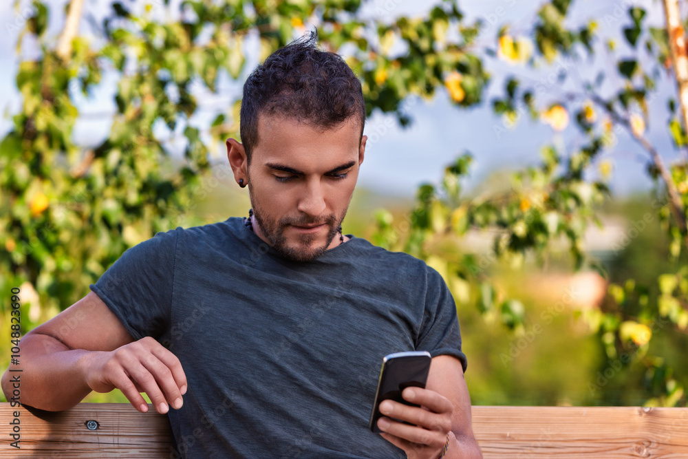 Young man using smartphone while relaxing on bench in park Young man using smartphone while relaxing on bench in park
