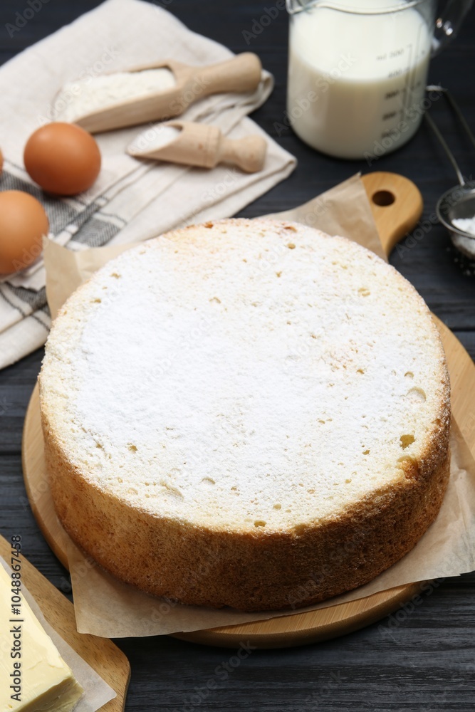 Delicious sponge cake and ingredients on black wooden table Delicious sponge cake and ingredients on black wooden table