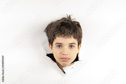 11 year old Brazilian child with only his head on a torn cardboard showing emotions_2. photo