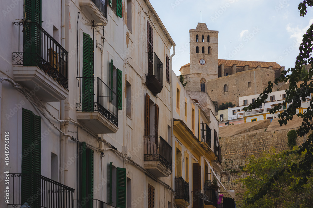 Scenic view of historic Dalt Vila and charming white buildings with green shutters in Ibiza’s Old Town, capturing Mediterranean elegance and cultural heritage. Scenic view of historic Dalt Vila and charming white buildings with green shutters in Ibiza’s Old Town, capturing Mediterranean elegance and cultural heritage.