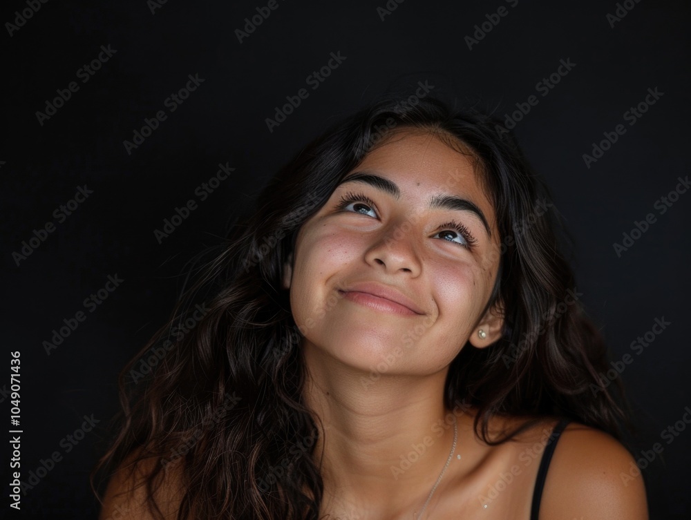 Woman with long hair is smiling and looking up at the camera. She is wearing a black tank top and necklace Woman with long hair is smiling and looking up at the camera. She is wearing a black tank top and necklace