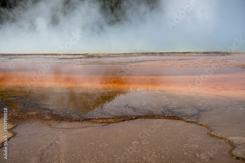 an active geyser spring with an intermittent discharge of water ejected turbulently and accompanied by steam photo