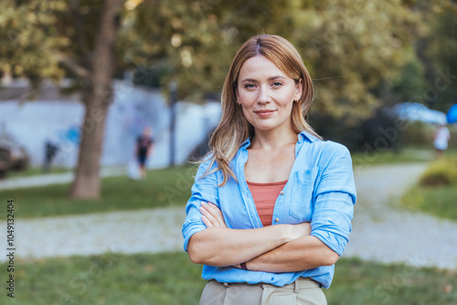 Confident Woman Standing in Park With Arms Crossed