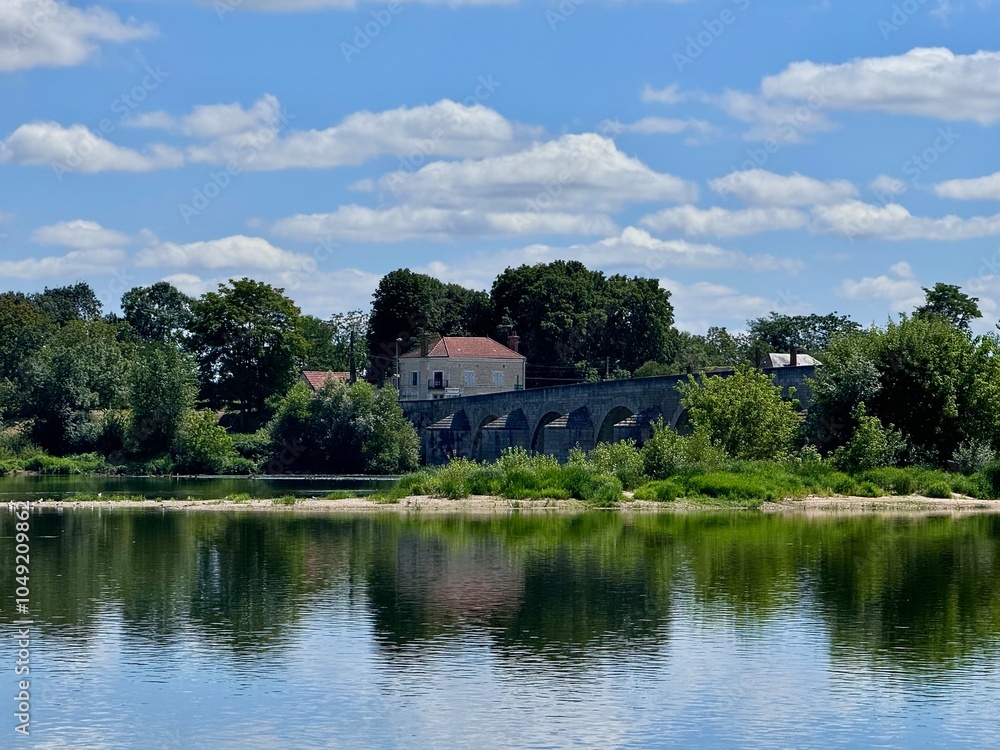 view of a stone bridge crossing the Loire in the French countryside on a summer day with green vegetation
view of a stone bridge crossing the Loire in the French countryside on a summer day with green vegetation