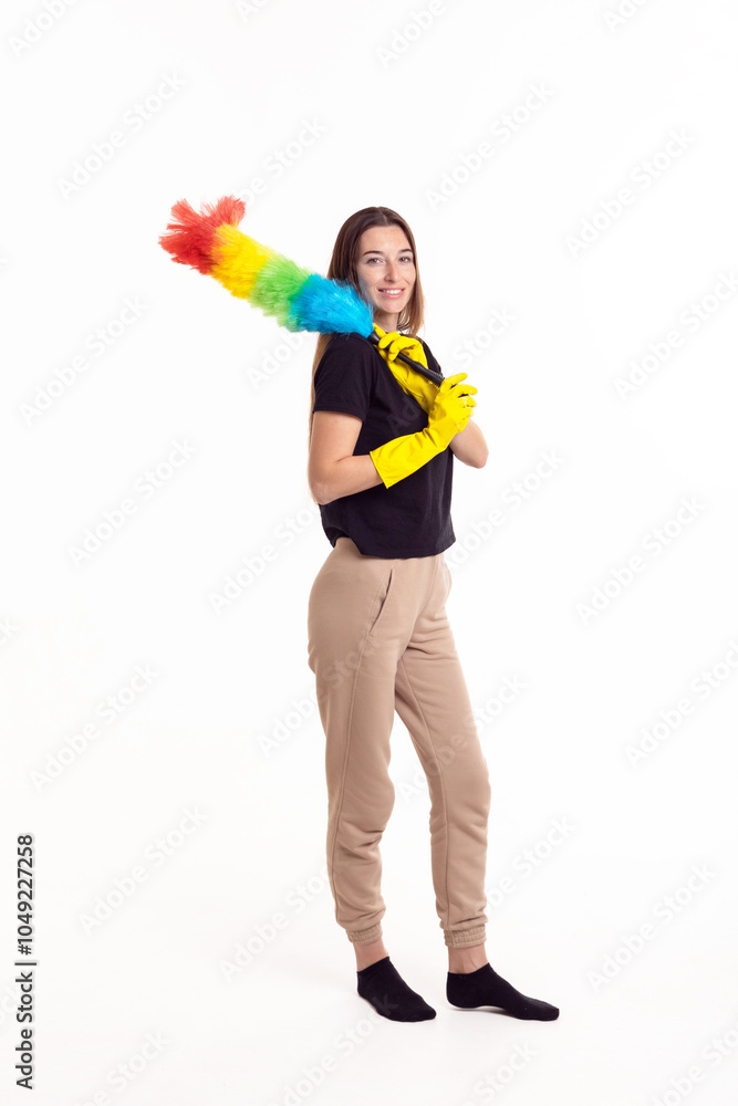 A smiling person in yellow cleaning gloves wields a colorful feather duster in a bright studio environment A smiling person in yellow cleaning gloves wields a colorful feather duster in a bright studio environment