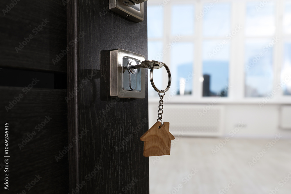 Open door with key and house shaped keychain, closeup. Space for text Open door with key and house shaped keychain, closeup. Space for text