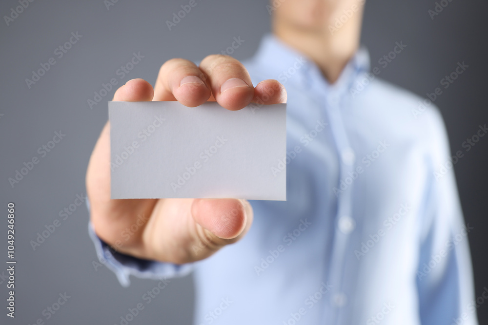Man holding blank business card on grey background, closeup. Mockup for design Man holding blank business card on grey background, closeup. Mockup for design