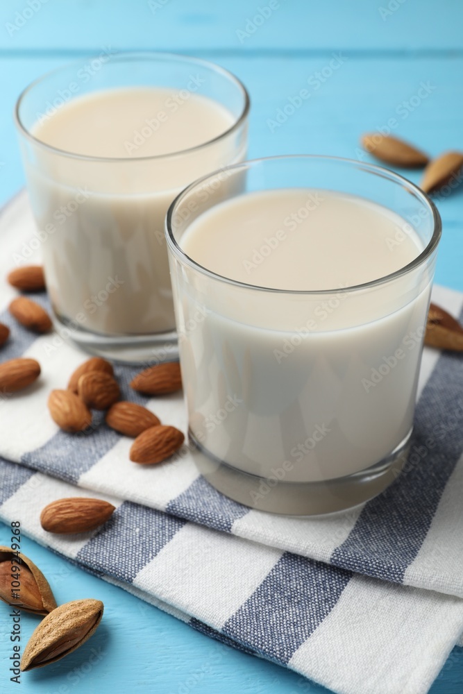 Glasses of almond milk and nuts on blue wooden table, closeup Glasses of almond milk and nuts on blue wooden table, closeup