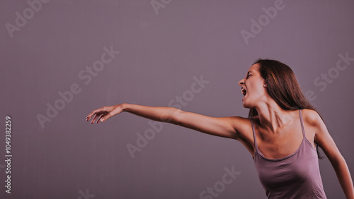 Young woman reaching and screaming on purple background