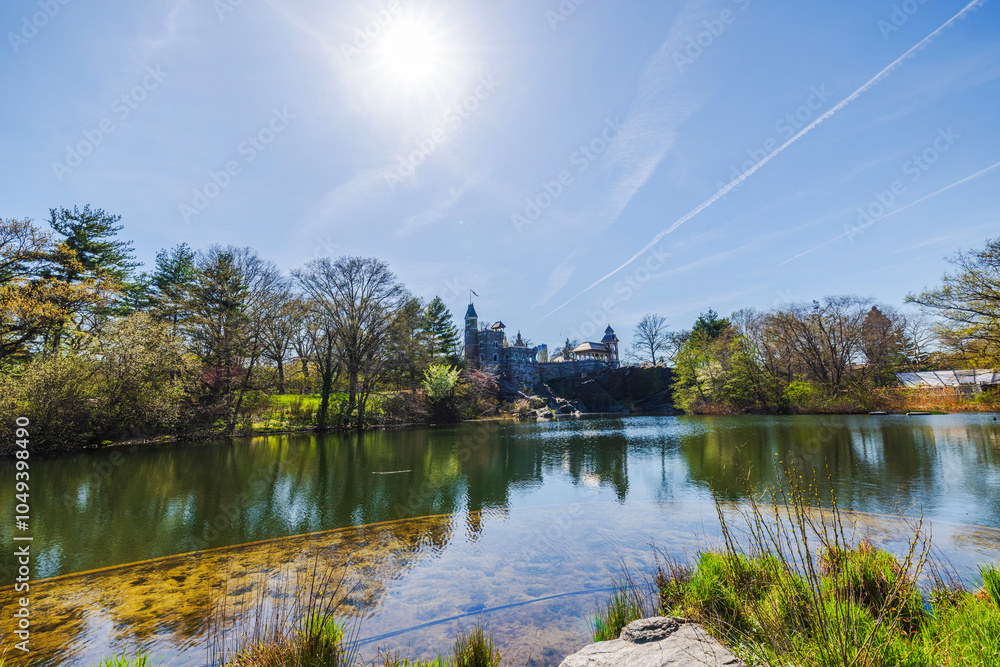 Sunny spring view of serene lake with trees and historic Belvedere castle in background under blue sky. New York. USA. Sunny spring view of serene lake with trees and historic Belvedere castle in background under blue sky. New York. USA.