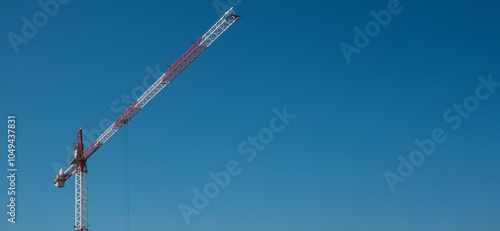 The crane works against the blue sky. Construction, investment, real estate sales. Space for text. Copy space