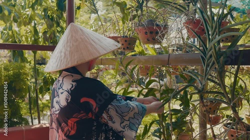 Asian person in conical hat working in the garden. photo