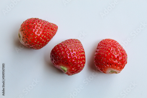 Fotografie Three red strawberries without the stem and leaves, isolated on white background