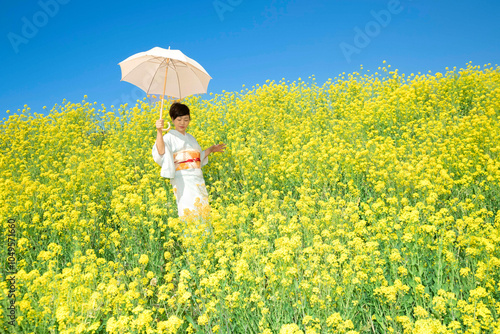 Wallpaper Mural A Japanese woman wearing kimono enjoys the spring season in beautiful yellow flowers, or nanohana, blooming in Japan. Torontodigital.ca
