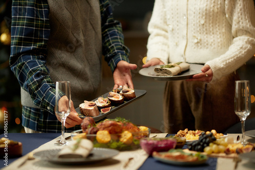 Cropped shot of man serving plate of tartines with figs and ricotta on dining table and woman helping while preparing for family Christmas dinner photo