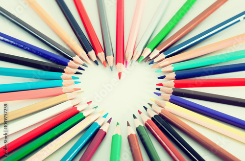 Colored pencils lying around the heart photo