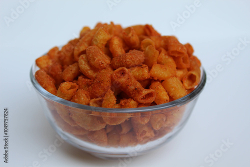 Spicy fried small macaroni crackers, inside glass bowl, on white background photo