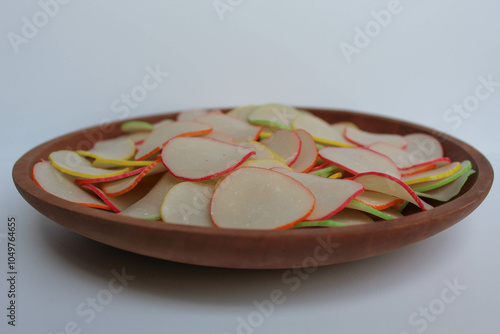 Kerupuk bawang pelangi, or garlic crackers with rainbow edge, from Indonesia. Before cooked. On wooden plate, isolated on white background
