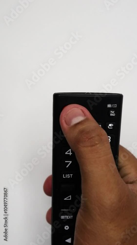 Wallpaper Mural A hand holding a TV remote control, representing technology in everyday life and media consumption. Torontodigital.ca