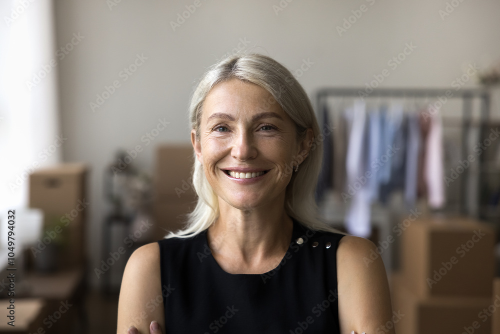 © fizkes - Headshot portrait of beautiful mid aged woman posing indoors with healthy toothy smile. Happy elderly female renter tenant buyer of new apartment flat office space looking at camera at relocation day