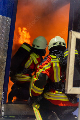 Trupp der freiwilligen Feuerwehr rückt mit Atemschutz Ausrüstung und Strahlrohr, zur Brandbekämpfung vor. photo