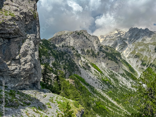 Scenic hiking trail surrounded by majestic steep mountain ridges of Albanian Alps (Accursed Mountains). Crossing high altitude pass between Valbone Valley and Thethi National Park, Albania. Wanderlust