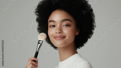 woman with radiant smile applies toxin free foundation using makeup brush, highlighting her natural beauty. soft lighting enhances her glowing complexion photo