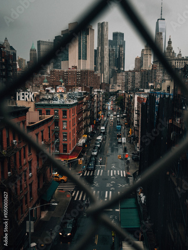 Photography View through fence of urban street with buildings and city skyline in background