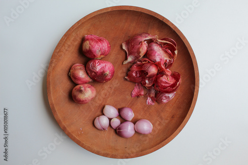 Shallots, before and after peeled, and shallot skin, on wooden plate, isolated on white background, flat lay or top view photo