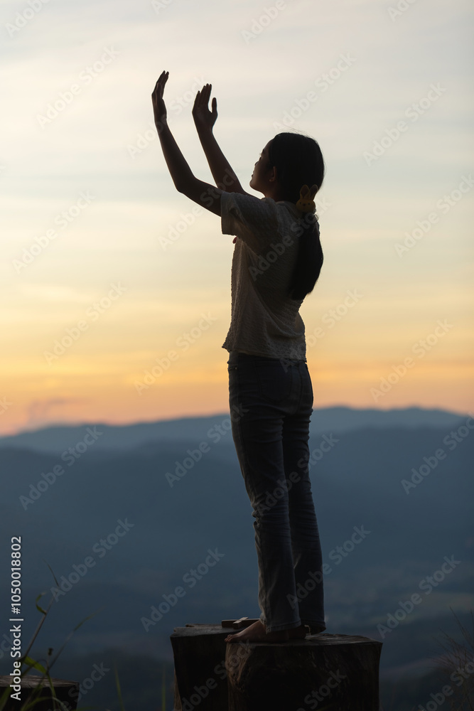Fototapeta premium Girl praying to God on the mountain sunset background.
