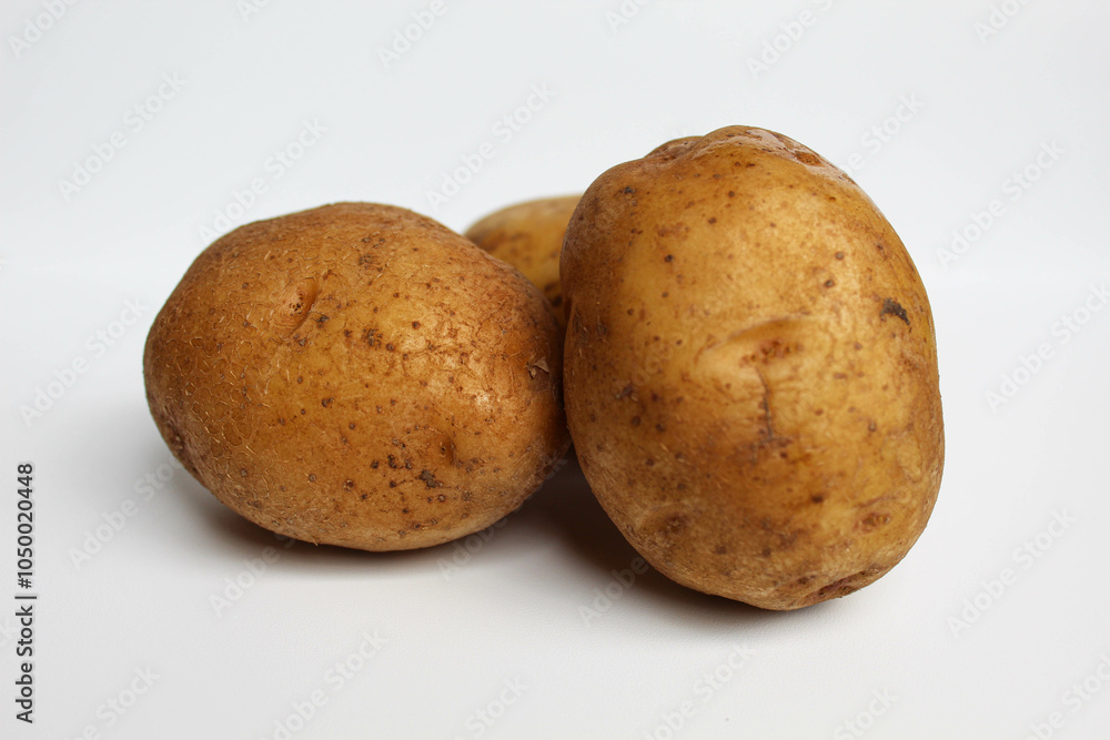 Fototapeta premium Three potatoes unpeeled, isolated on white background