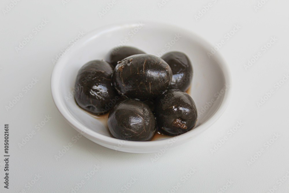 Table olives or fermented black olive, in small white bowl, isolated on white background Table olives or fermented black olive, in small white bowl, isolated on white background