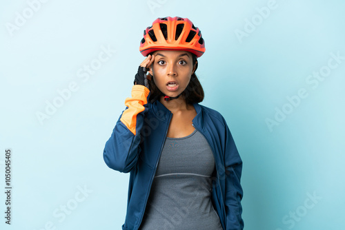 Young cyclist woman isolated on blue background has realized something and intending the solution