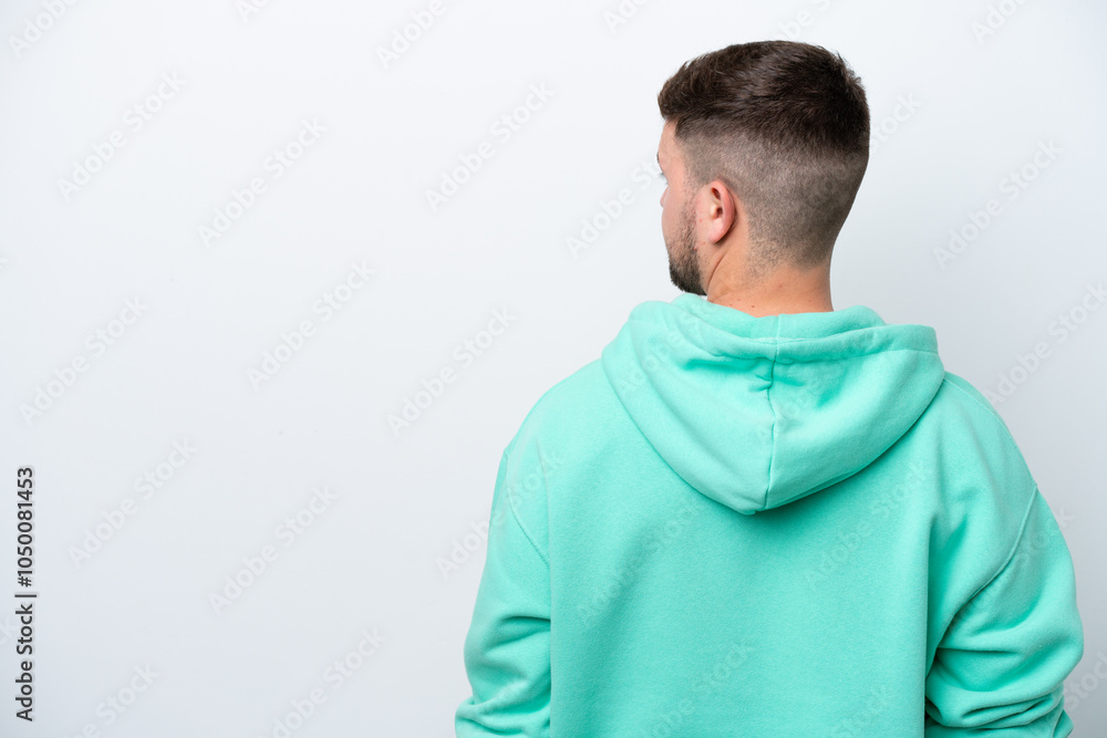 Young caucasian man isolated on white background in back position and looking side Young caucasian man isolated on white background in back position and looking side