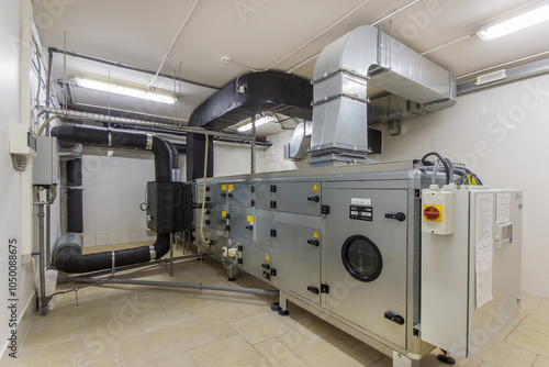 Fotografie A large air handling unit is installed in a commercial utility room, featuring extensive ductwork and control panels, ensuring efficient air circulation and ventilation
