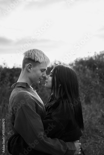 A 15-year-old teenage couple in love hugs and kisses at sunset