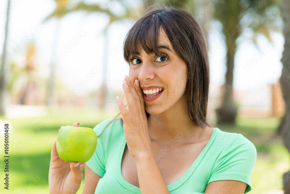 Young woman with an apple at outdoors whispering something Young woman with an apple at outdoors whispering something