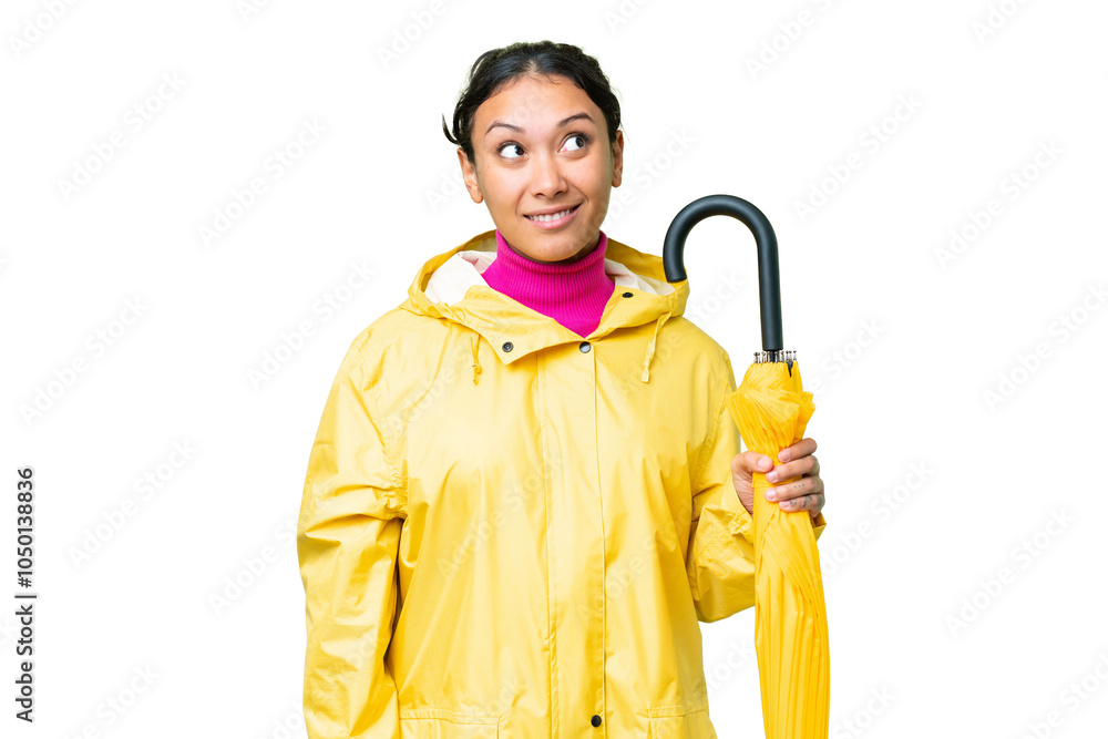 Young Uruguayan woman with rainproof coat and umbrella over isolated chroma key background thinking an idea while looking up Young Uruguayan woman with rainproof coat and umbrella over isolated chroma key background thinking an idea while looking up