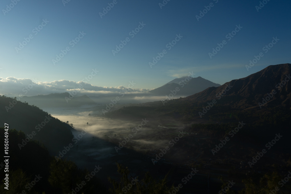 A breathtaking view of a foggy morning in the valley with mountains in the background. A breathtaking view of a foggy morning in the valley with mountains in the background.
