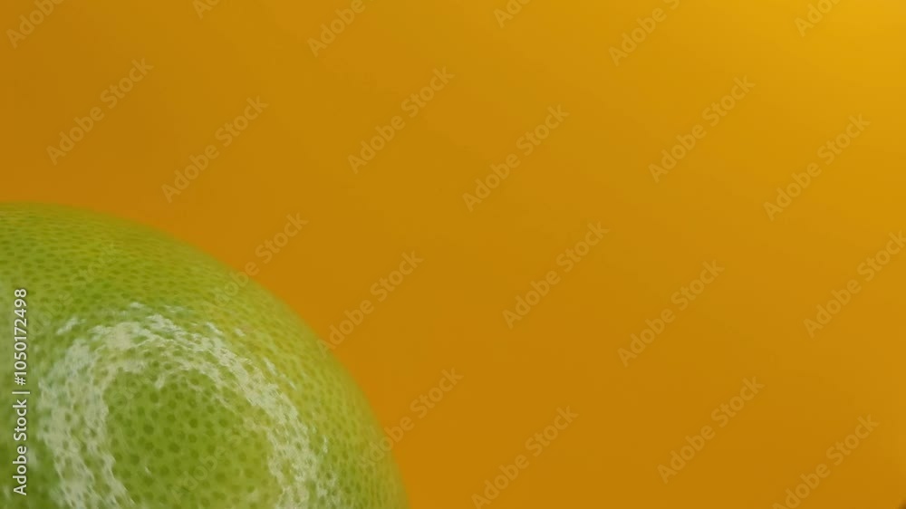 Rotating green grapefruit on a yellow background.